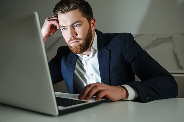Mann sitzt mit sorgenvollem Gesicht vor seinem Laptop
